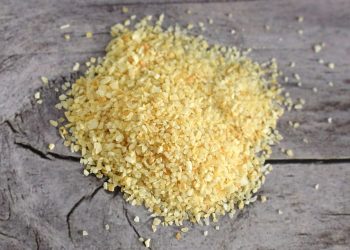 Coarse bulgur grains scattered on a wooden table.