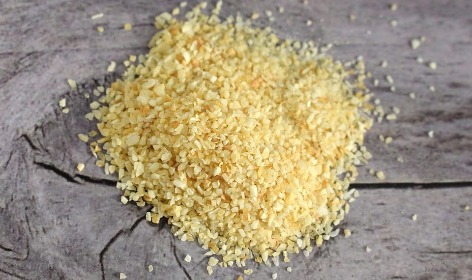 Coarse bulgur grains scattered on a wooden table.