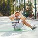 Man doing sit-ups on a green mat outdoors, focusing on exercise.