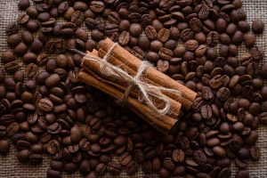Cinnamon sticks tied with twine on coffee beans background.