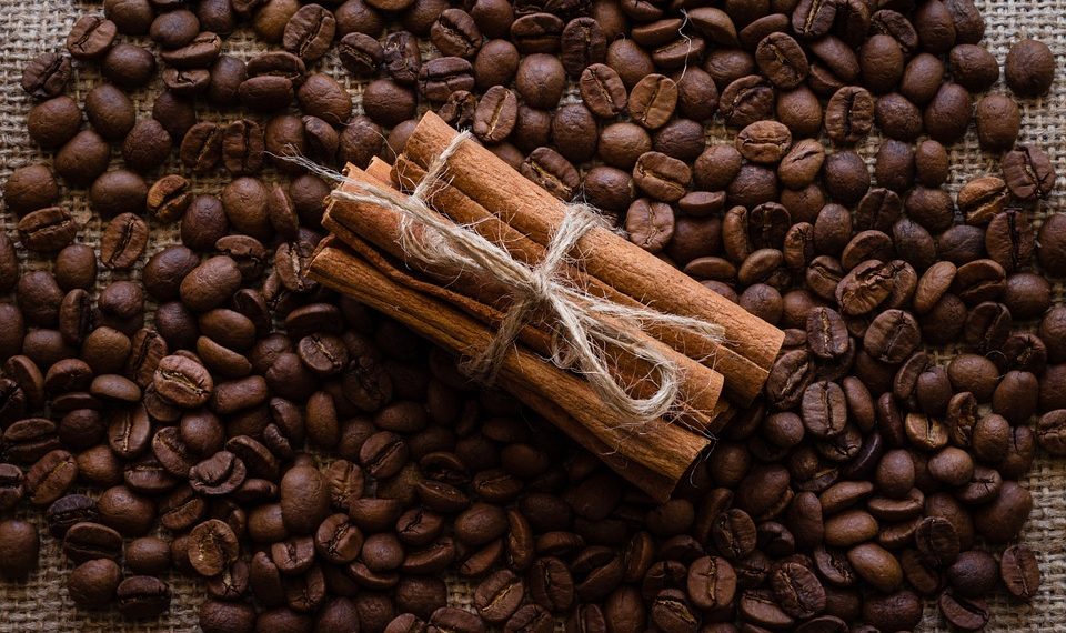 Cinnamon sticks tied with twine on coffee beans background.