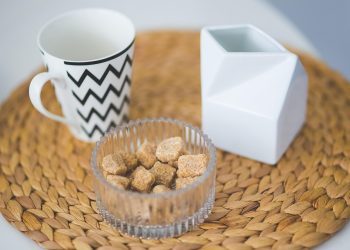 Chevron mug with sugar cubes in bowl on woven placemat.