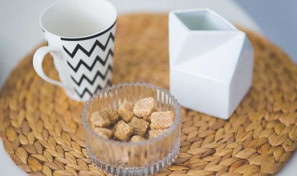 Chevron mug with sugar cubes in bowl on woven placemat.
