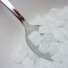 Silver spoon scooping crystal sugar cubes from a bowl.