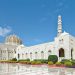 Grand mosque exterior with gardens under blue sky.