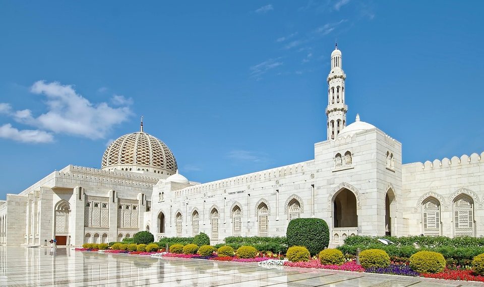 Grand mosque exterior with gardens under blue sky.