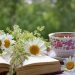 Flowery tea setup with an open book and daisies.