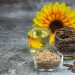 Sunflower seeds, oil, and flower displayed on a table.