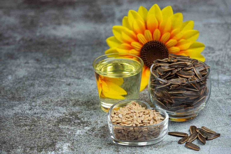 Sunflower seeds, oil, and flower displayed on a table.