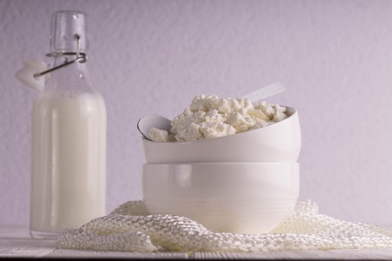 Cottage cheese in a bowl with a milk bottle in the background.
