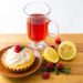 Lemon tart with raspberry and red tea on wooden table.