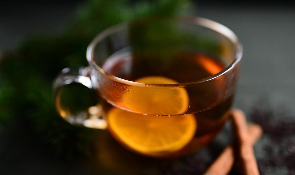Warm cup of tea with lemon slices and cinnamon sticks.