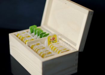Assorted tea bags organized in a wooden box.