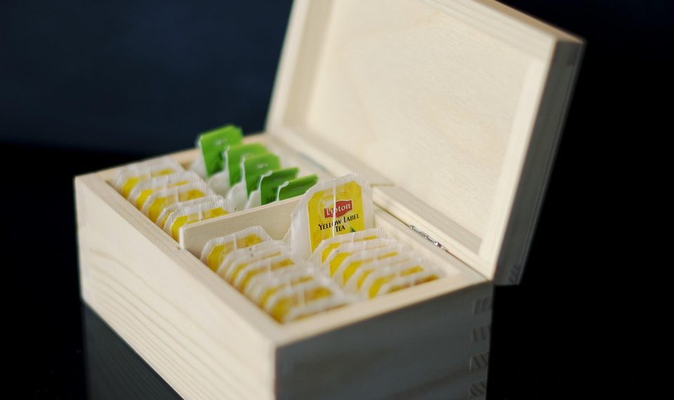 Assorted tea bags organized in a wooden box.