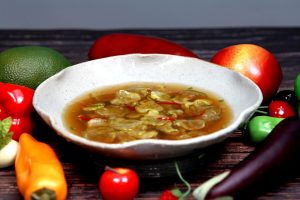 Bowl of vegetable soup with colorful fresh produce.