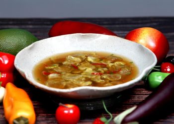Bowl of vegetable soup with colorful fresh produce.