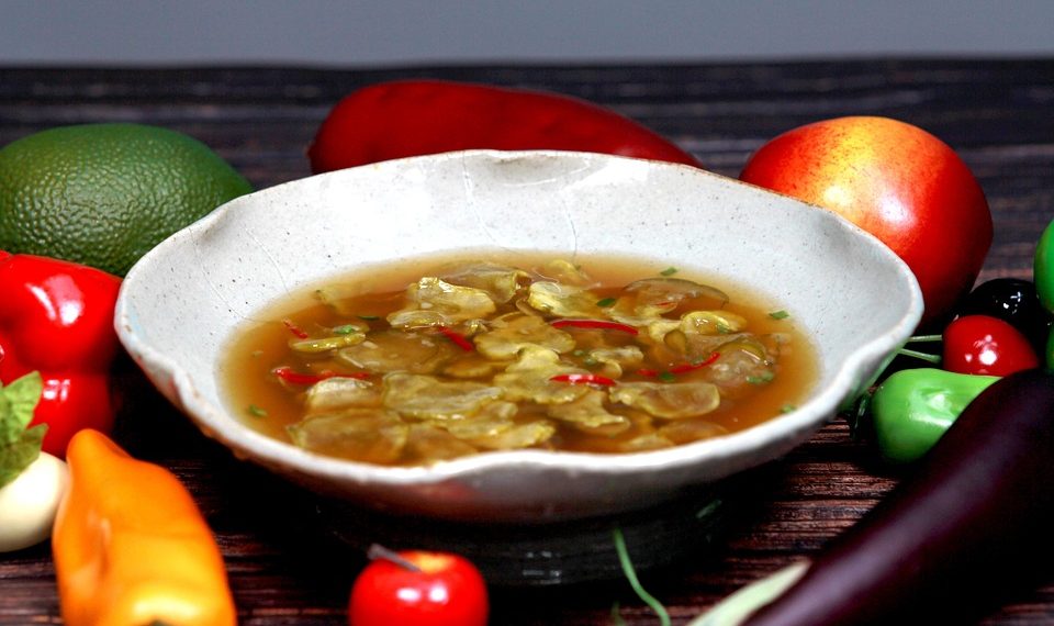 Bowl of vegetable soup with colorful fresh produce.