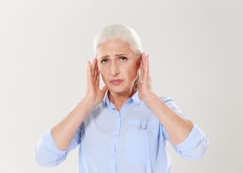 Senior woman holding her ears in discomfort.