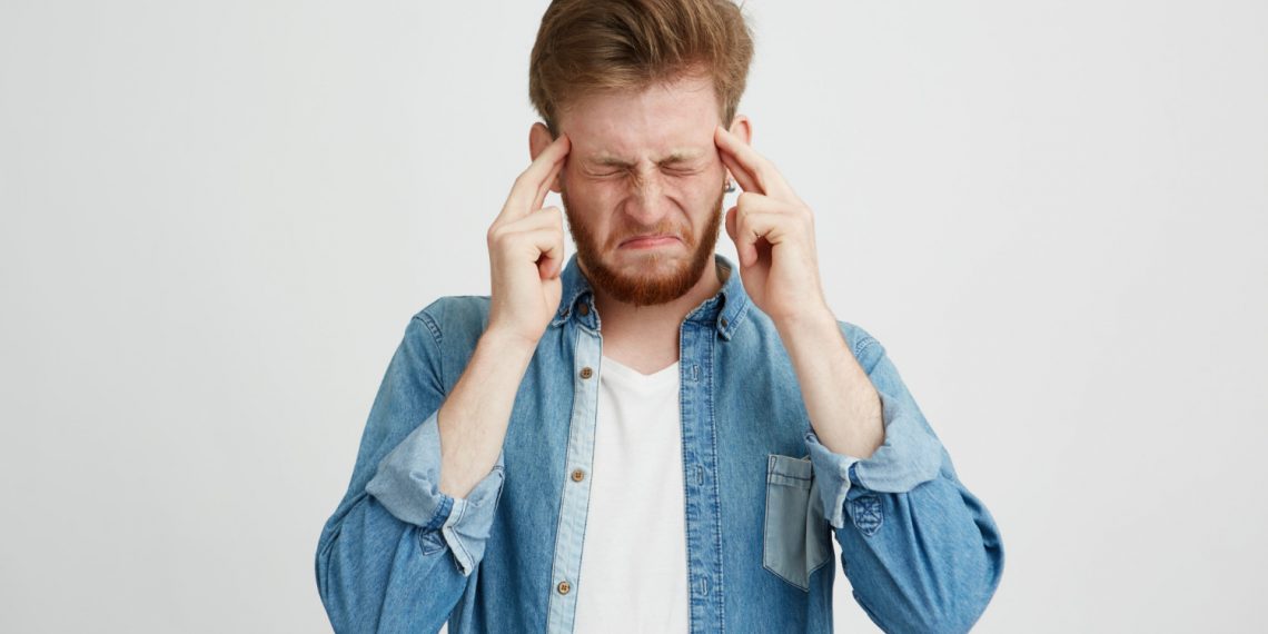 Man in denim shirt holding head in frustration