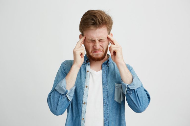 Man in denim shirt holding head in frustration