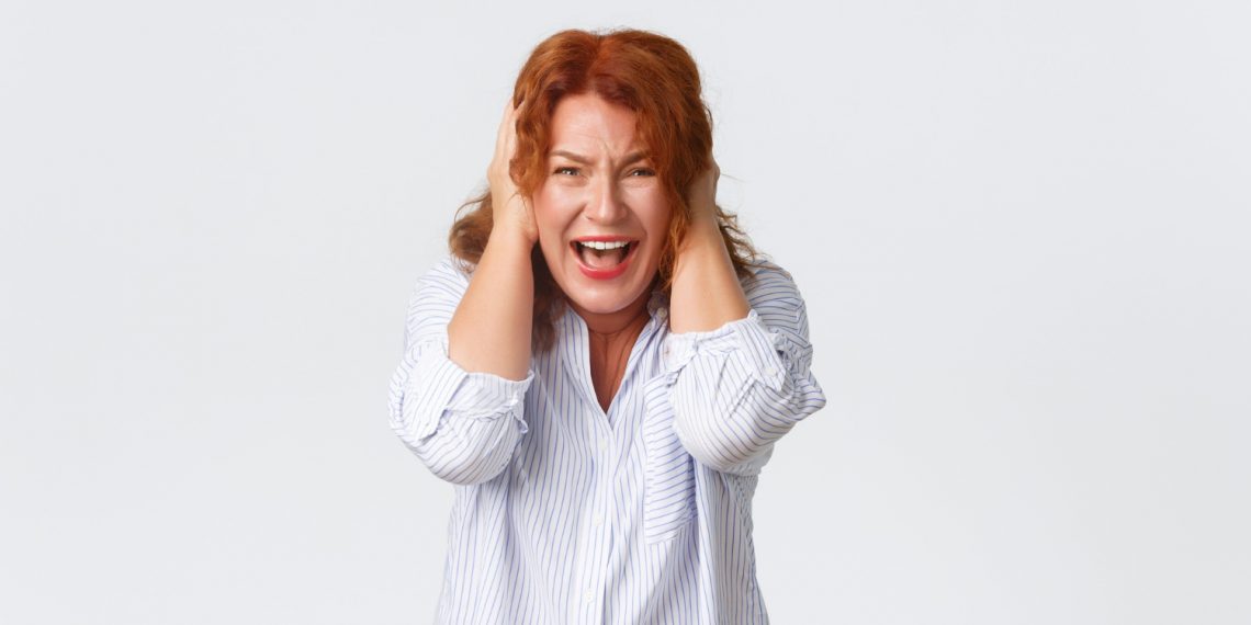 Woman expressing stress with hands on head.