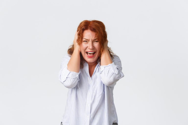 Woman expressing stress with hands on head.