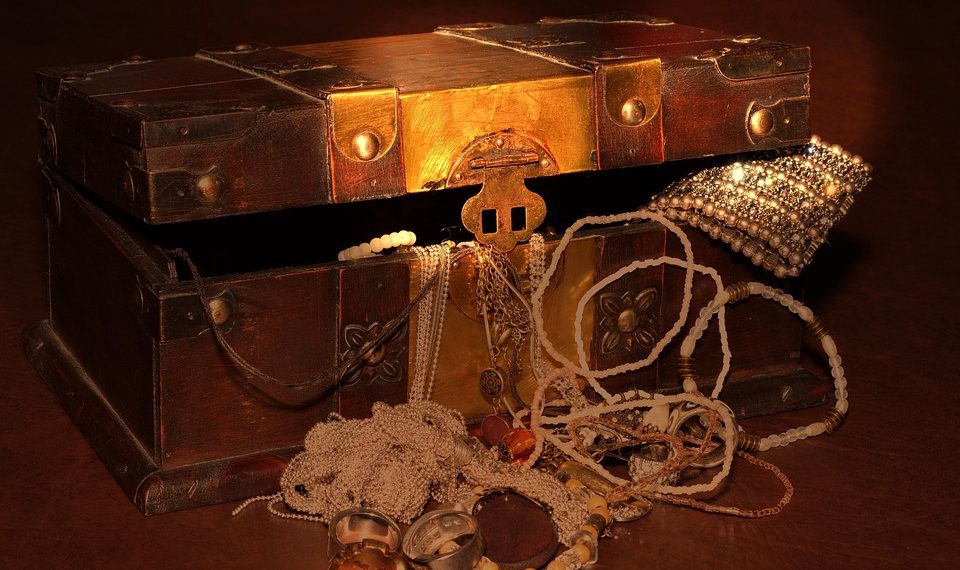 Antique treasure chest filled with jewelry and gold.