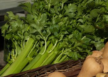 Fresh celery stalks in a wicker basket at a market.