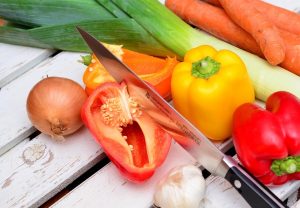 Vegetables and knife on wooden table.
