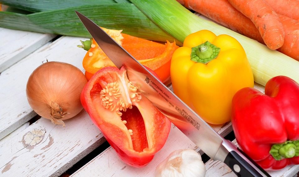 Vegetables and knife on wooden table.