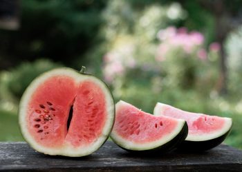 Sliced watermelon on a wooden table outdoors.