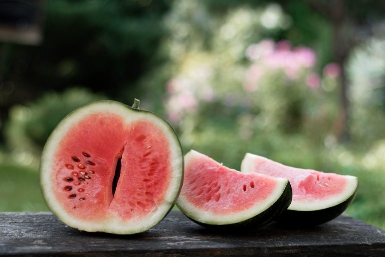 Sliced watermelon on a wooden table outdoors.