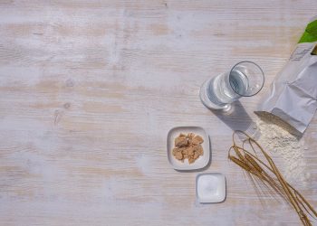 Baking ingredients including flour, yeast, and water on a wooden table.