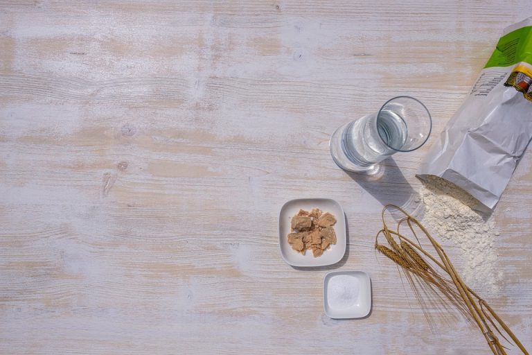 Baking ingredients including flour, yeast, and water on a wooden table.