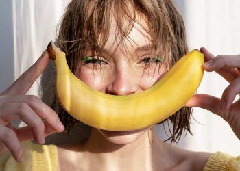 Woman smiling with banana in sunlight.
