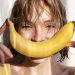 Woman smiling with banana in sunlight.
