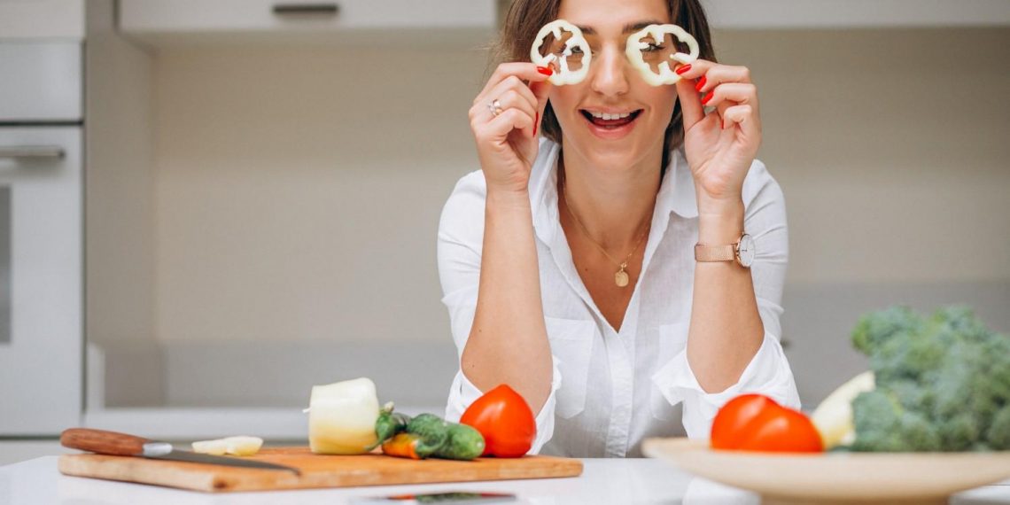 woman playfully holding bell pepper slices to eyes