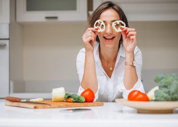 woman playfully holding bell pepper slices to eyes