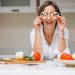 woman playfully holding bell pepper slices to eyes