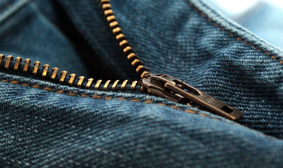 Close-up of a blue denim jeans zipper slightly undone.