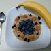 Oatmeal topped with blueberries, apple chunks, raisins, and a banana on the side.