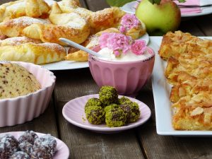 Assorted pastries and desserts with a bowl of cream topped with pink flowers.