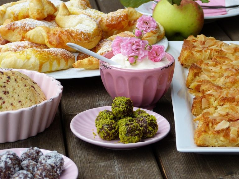 Assorted pastries and desserts with a bowl of cream topped with pink flowers.