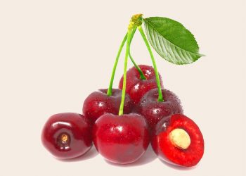 Fresh red cherries with a leaf, one cut open.