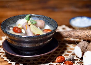 A hearty yam soup with vegetables in a rustic bowl.