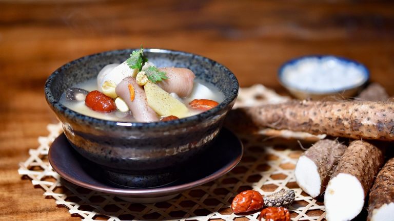 A hearty yam soup with vegetables in a rustic bowl.