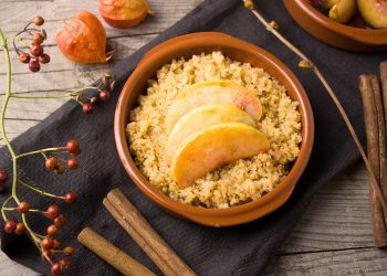 Quinoa topped with apple slices in a terracotta bowl.