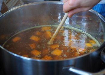 Cooking pumpkin soup in a pot with fresh ingredients.