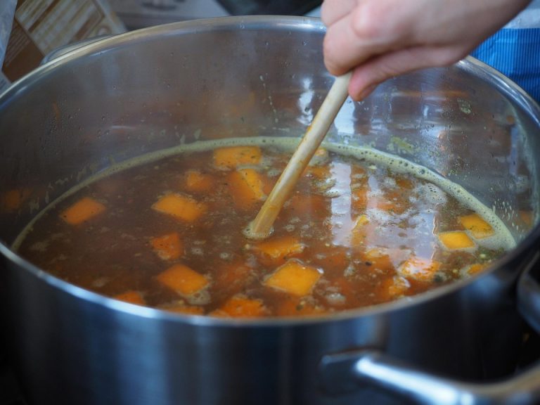 Cooking pumpkin soup in a pot with fresh ingredients.