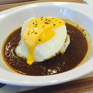 Poached egg on a rich beef curry rice dish.